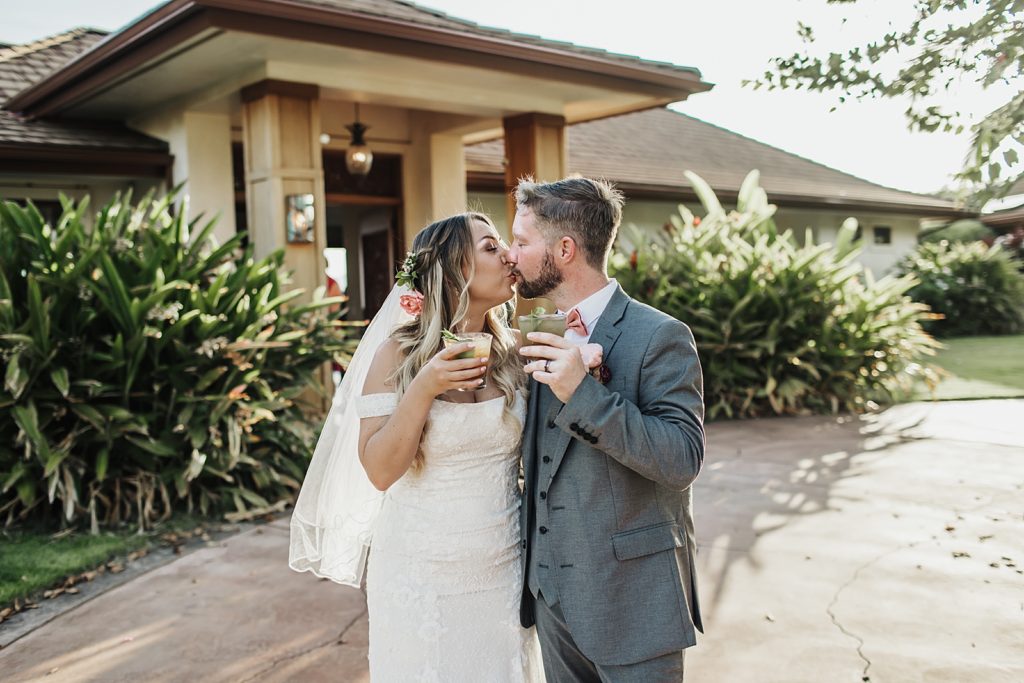 Bride and Groom kissing while holding cocktail drinks