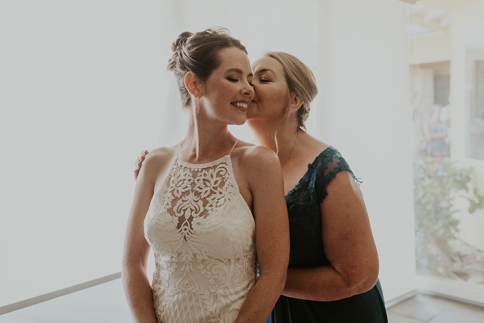 Mother kissing Bride on cheek after helping get her ready 