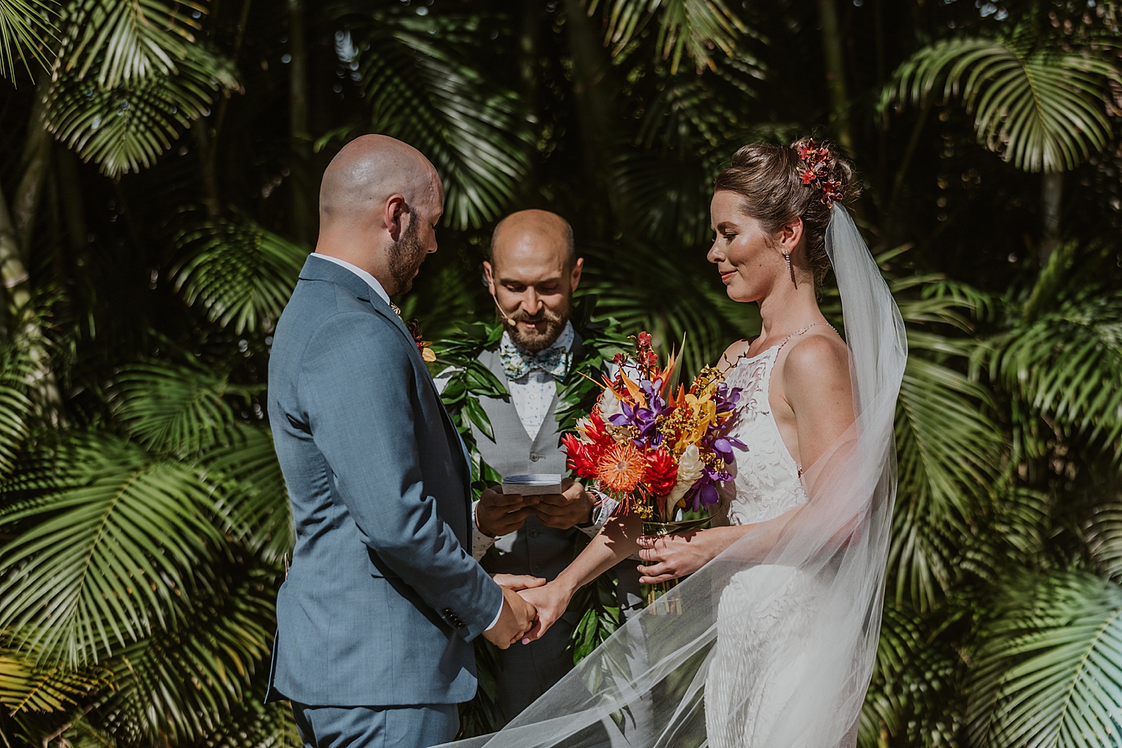 Bride and Groom holding hands with Bride holding tropical bouquet