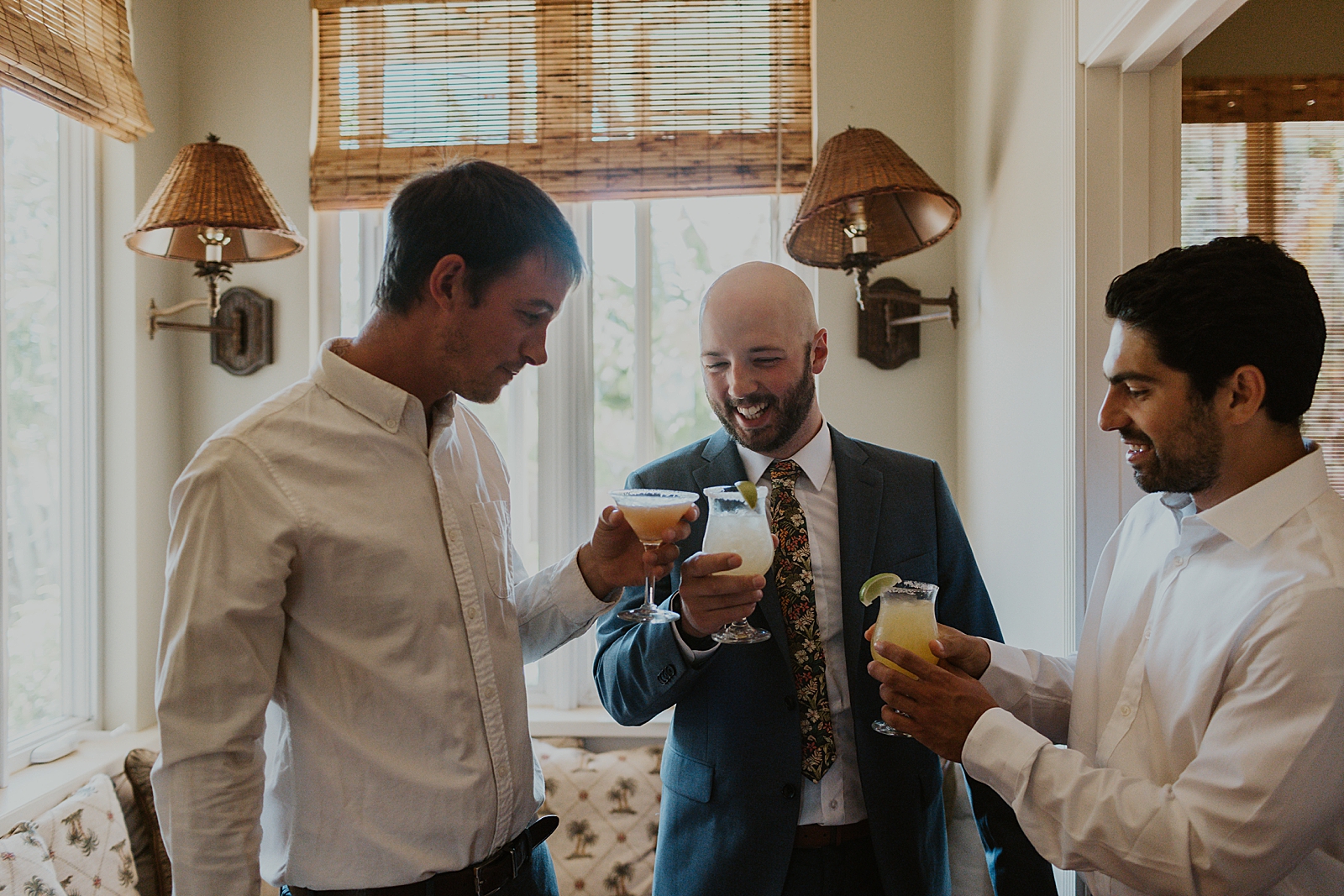 groom cheering cocktail drinks inside after getting ready 