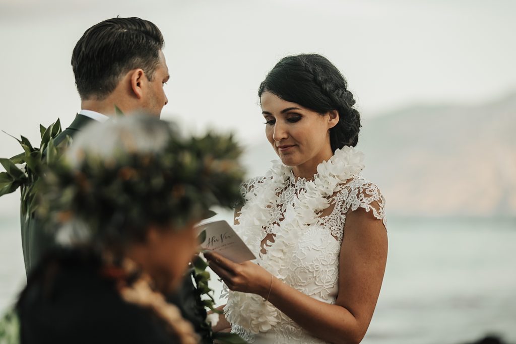 Bride reading off vow book to Groom on the beach
