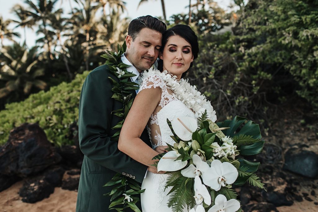 Groom holding Bride by the greenery on the beach