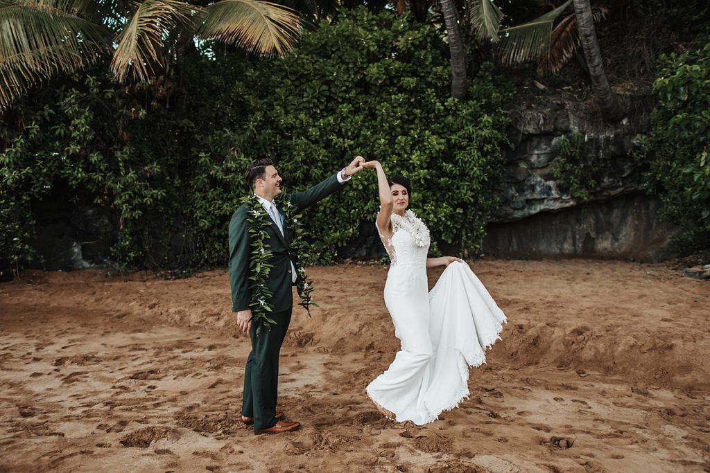 Bride twirling by Groom's hand on the sand of the beach