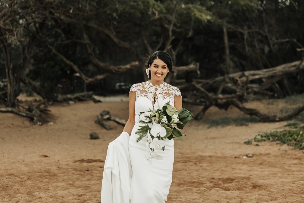 Bride walking with white bouquet on the sand