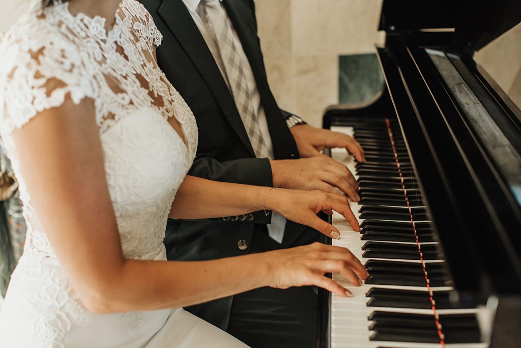 Closeup of Bride and Groom playing piano together 
