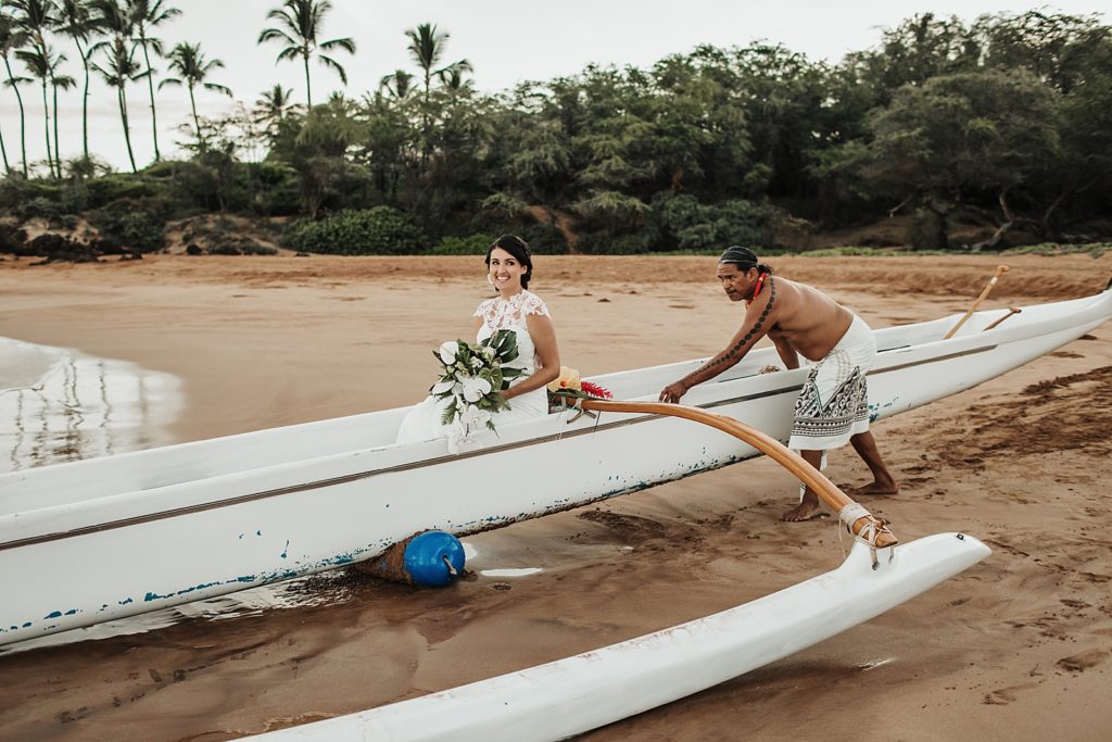 Bride in Hawaiian boat being pushed out by professional sailor 