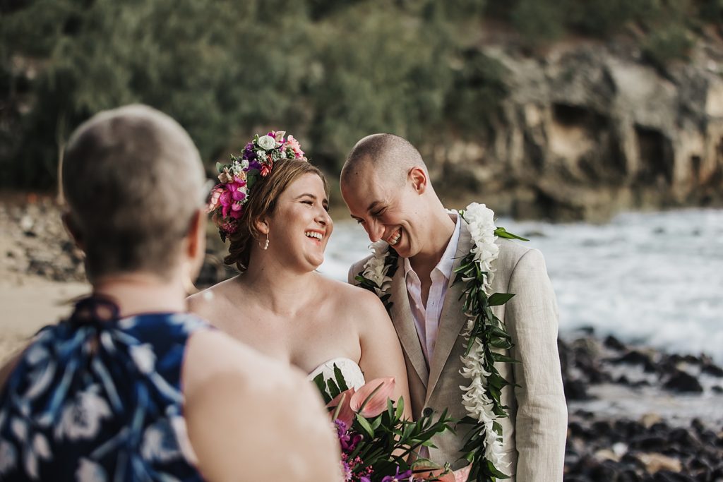 Bride and Groom laughing together listening to elopement speech by the ocean