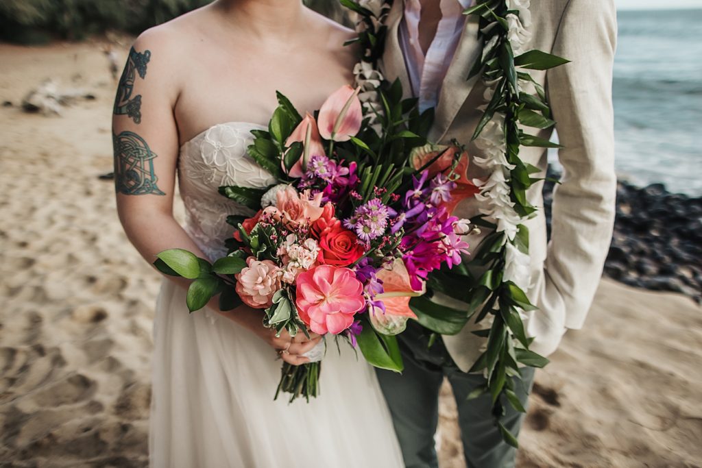 Closeup of Bride holding colorful bouquet with Groom by side