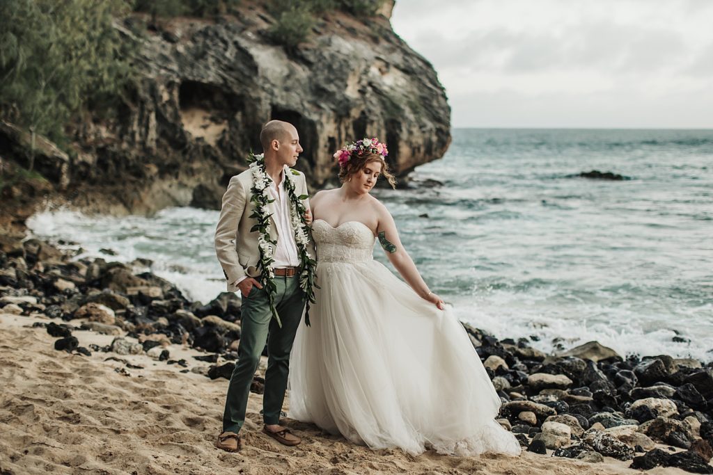 Bride and Groom side by side on the sand by the rocks by the ocean