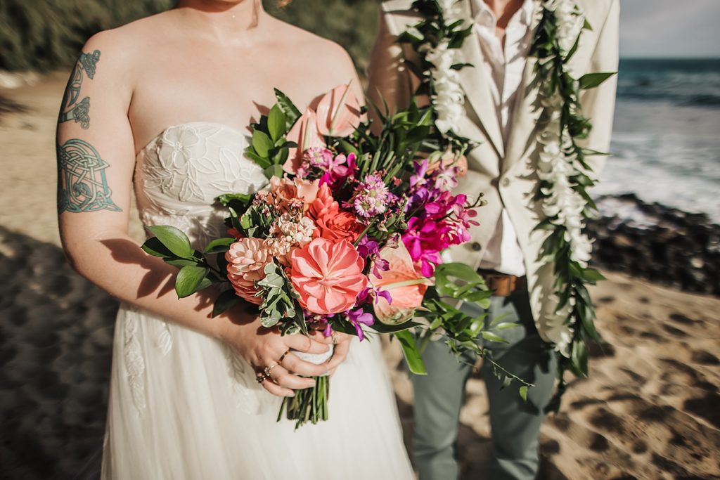 Closeup of Bride holding colorful bouquet and Groom with vine around shoulder