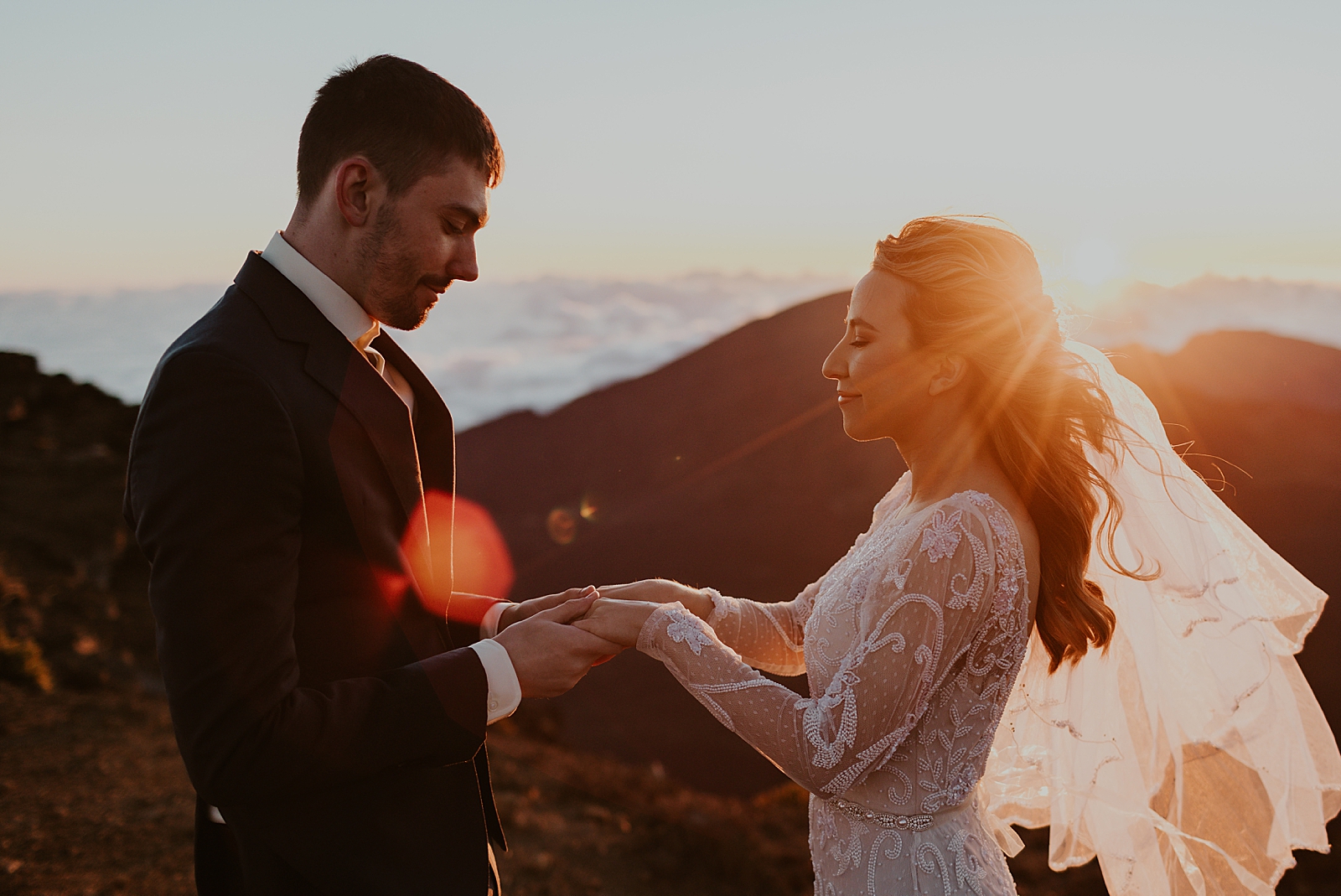 Bride and Groom holding hands on a mountain as the sun sets