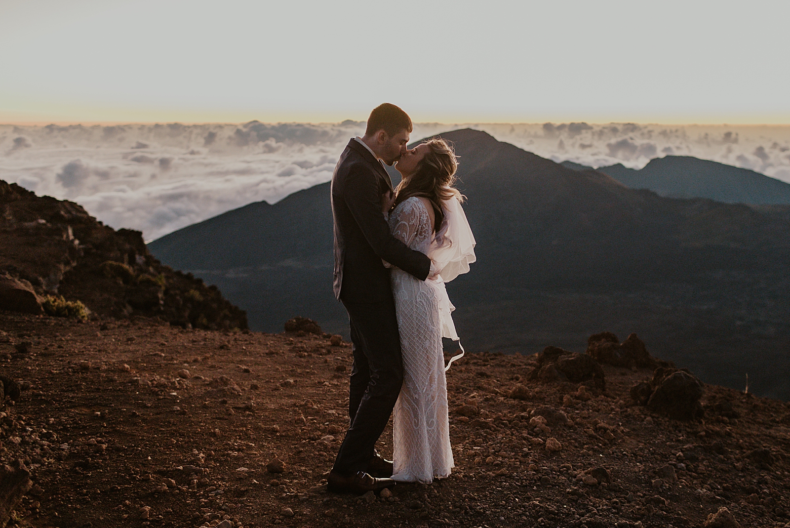 Bride and Groom kissing with mountains touching the clouds in front of them