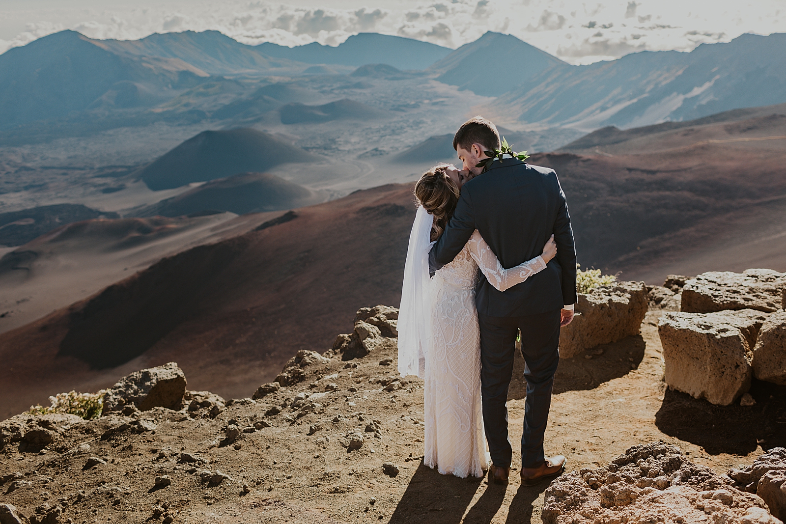 Bride and Groom kissing each other side by side looking down mountain