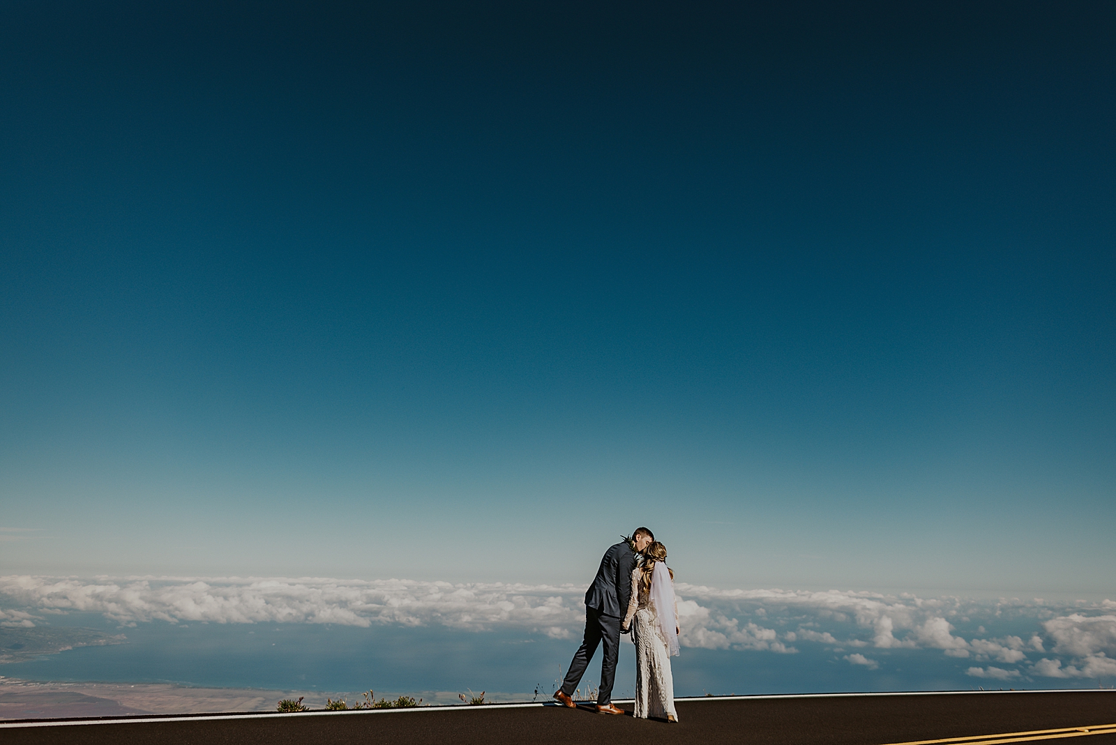 Bride and Groom kissing with the cloudy horizon in front of them