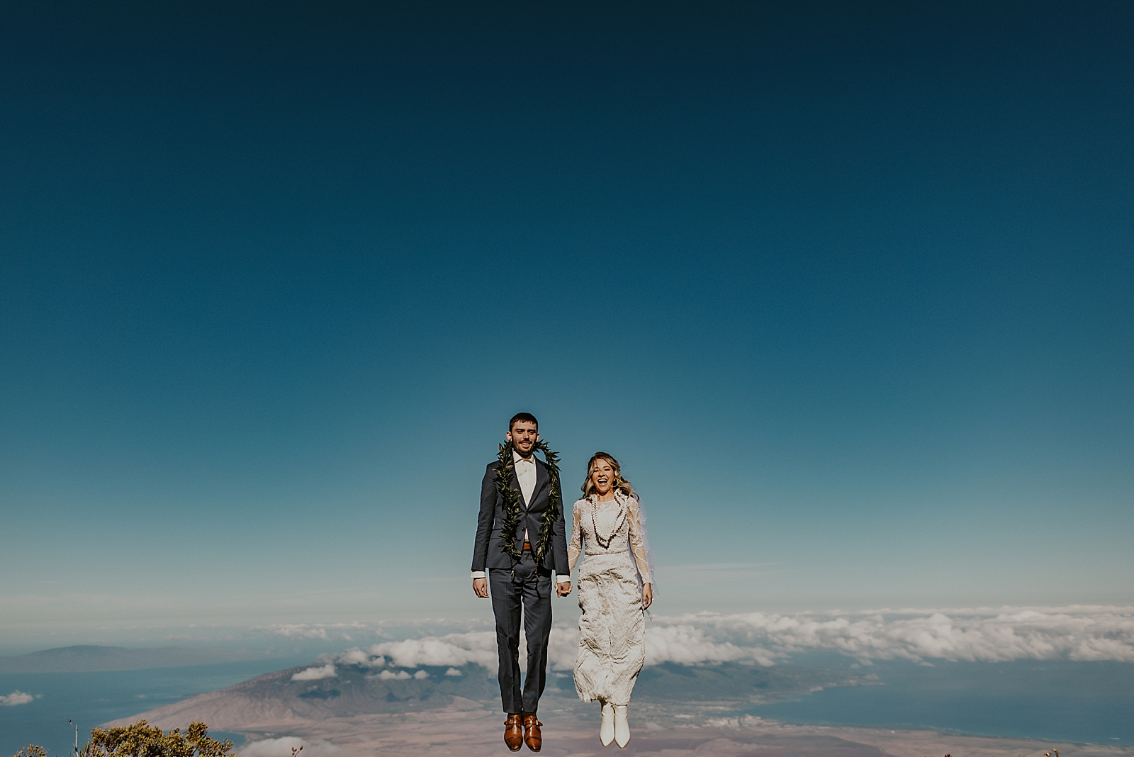 Bride and Groom jumping looking like they are above the clouds