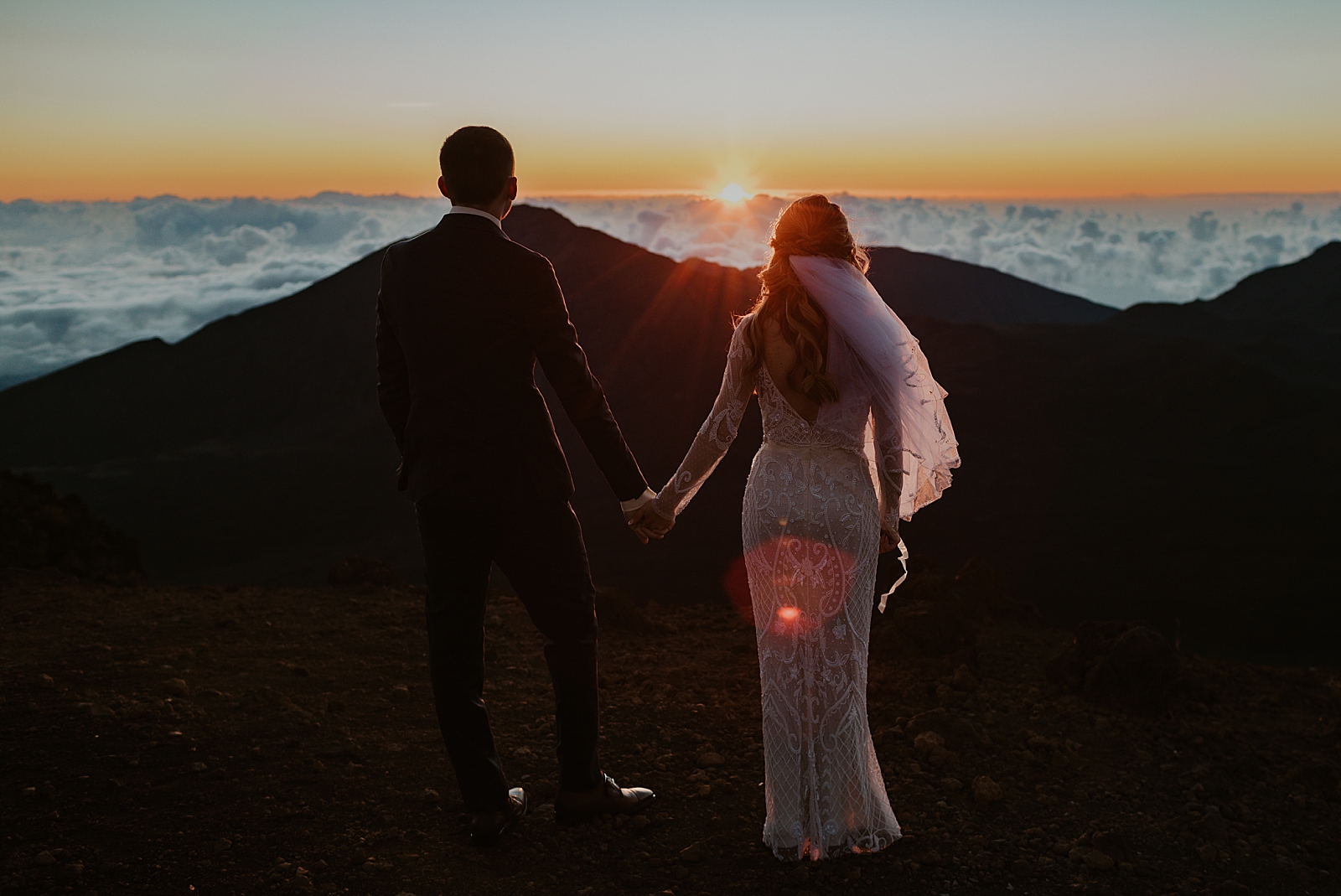 Bride and Groom holding hands watching the sun set