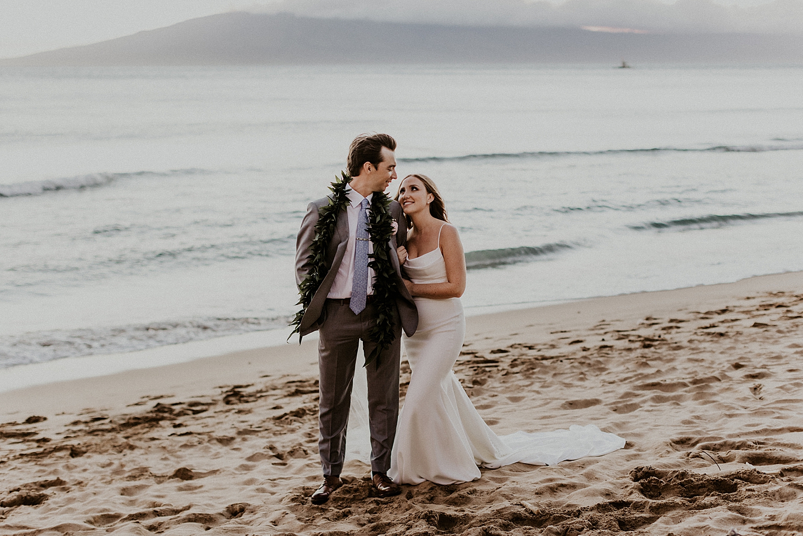 Bride holding Groom's arm and looking at him by the ocean water