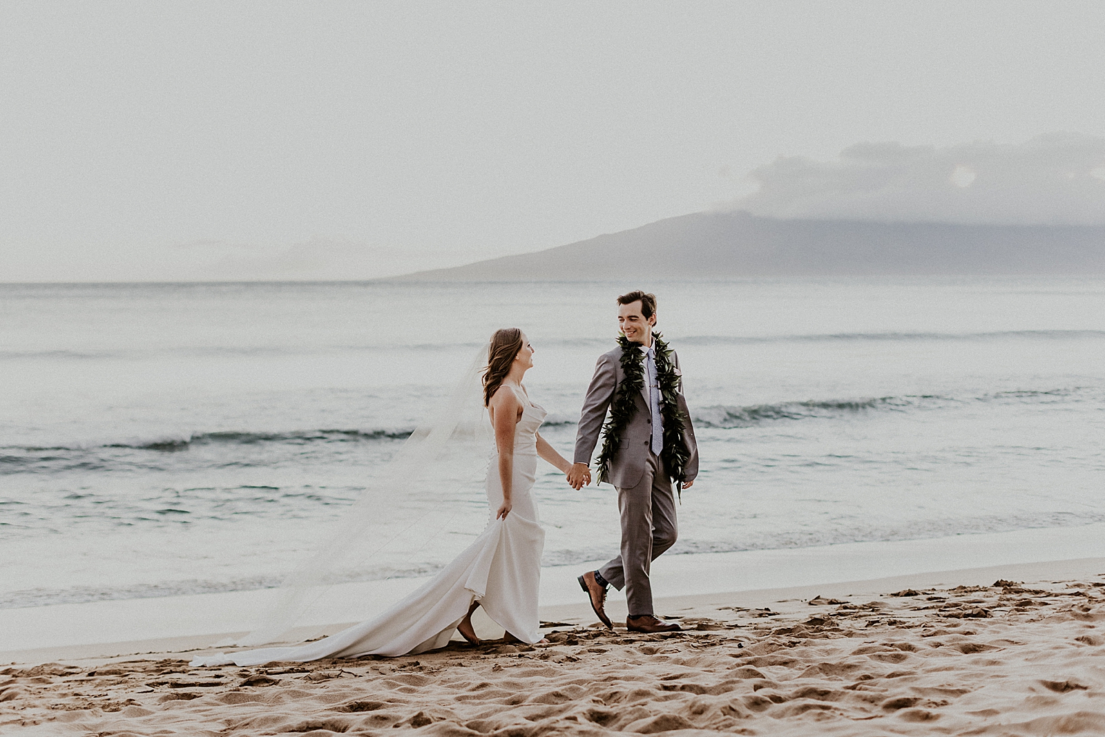 Bride and Groom holding hands and walking by the ocean on the beach