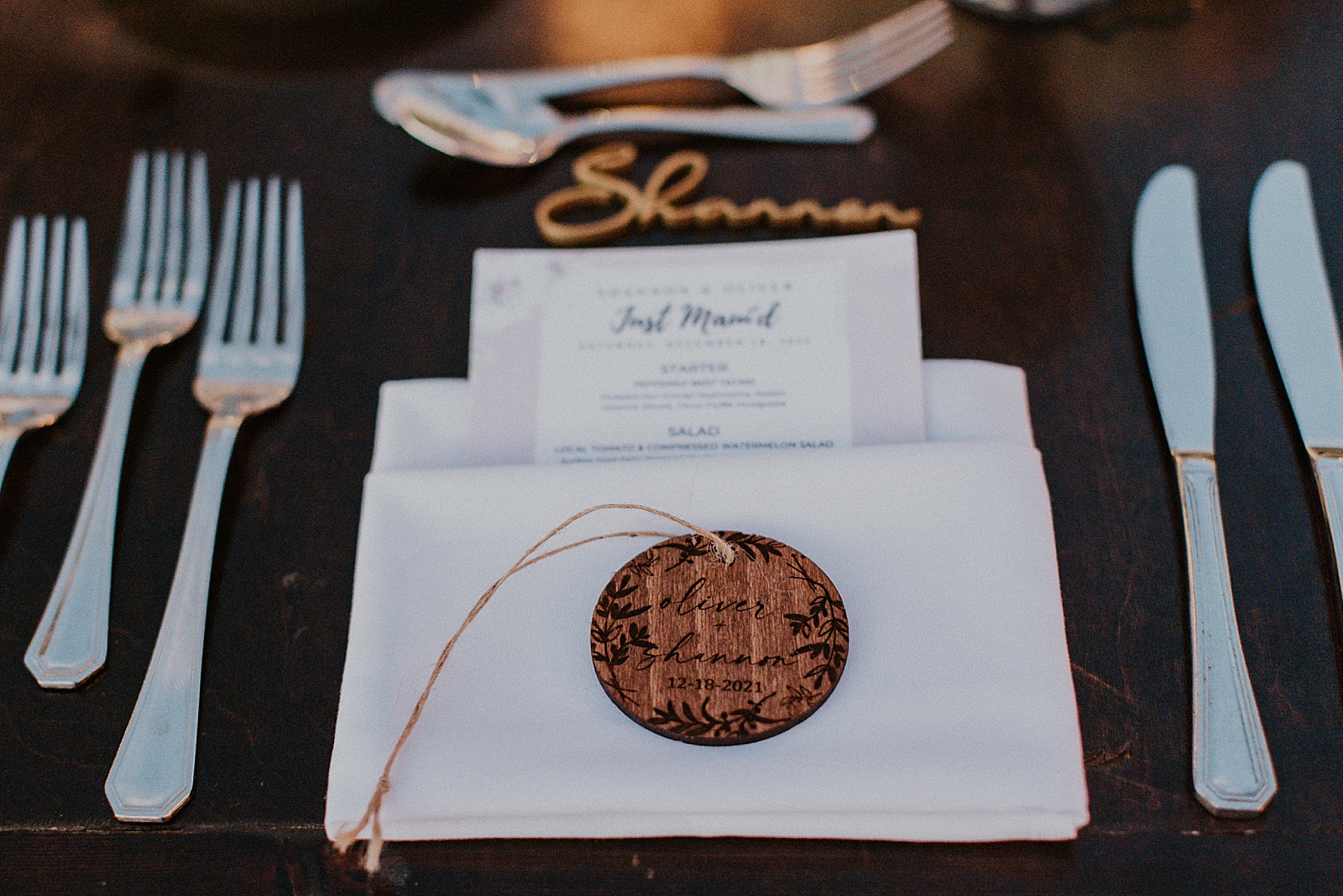 Detail shot of place setting of custom menu in napkin fold with forks and butter knives