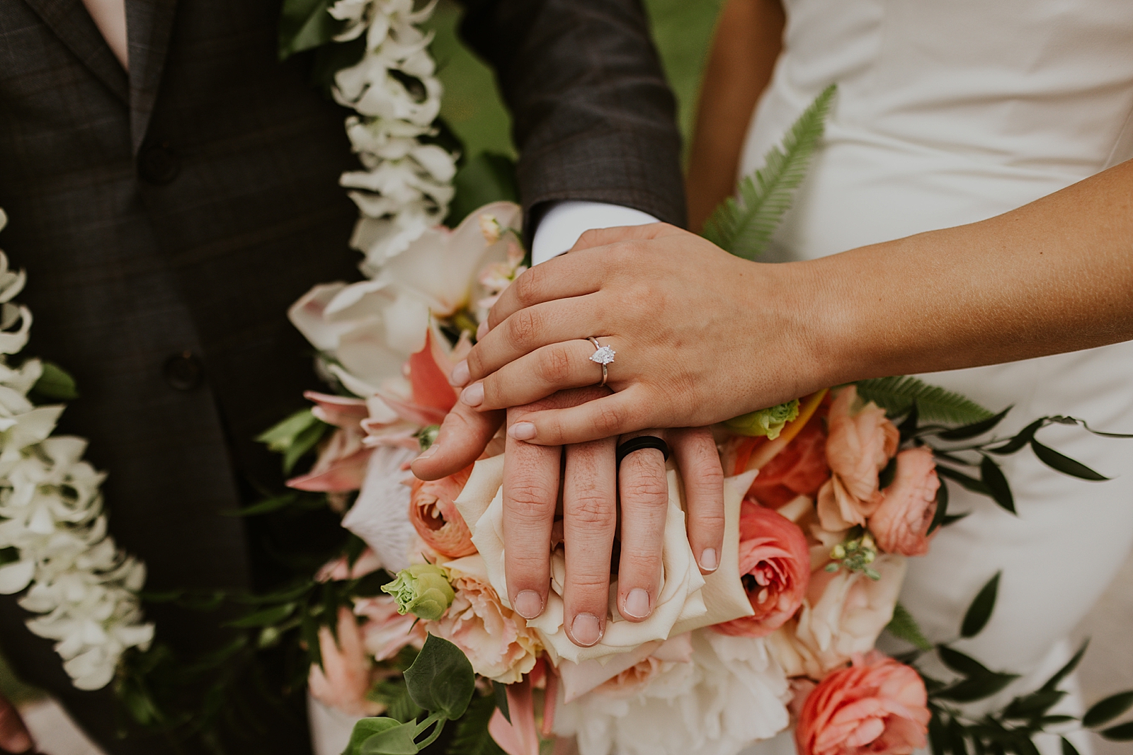 Closeup of Bride and Groom holding hands on top of bouquet