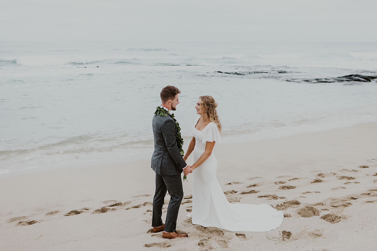 Bride and Groom holding hands on the beach by the ocean