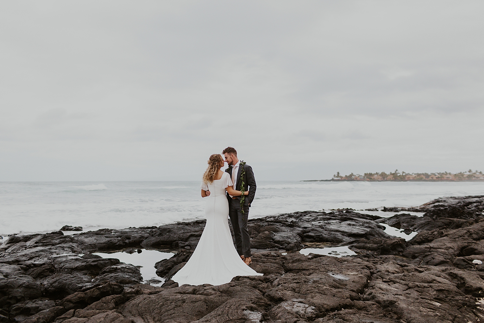 Bride and Groom holding each other standing on rocks by the ocean