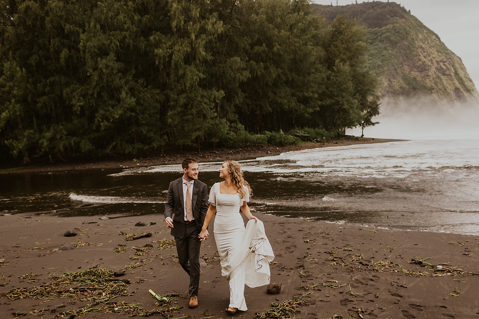 Bride and Groom walking on the wet dirt holding hands and looking at each other