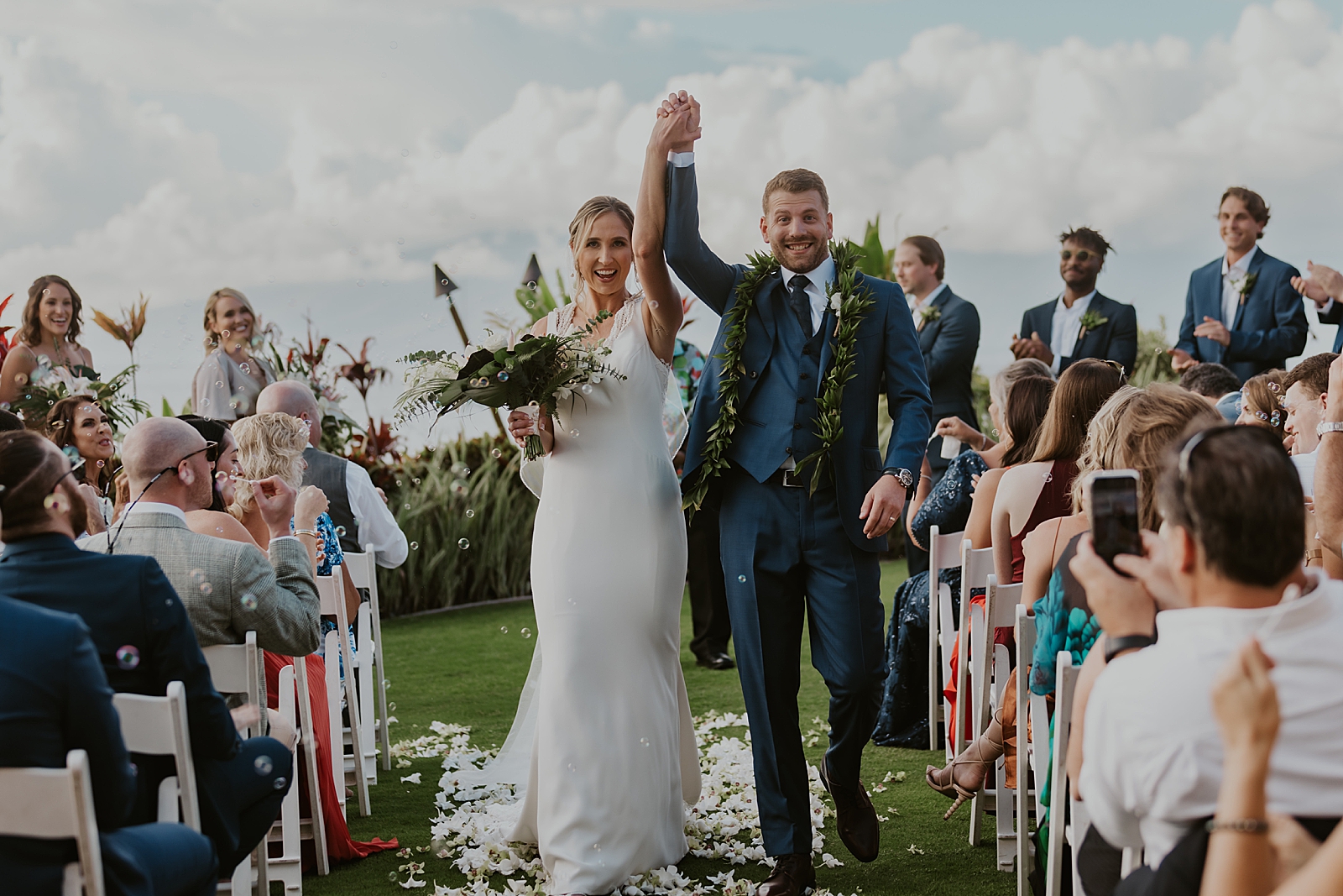 Quirky Bride and Groom holding hands up celebrating exiting Ceremony