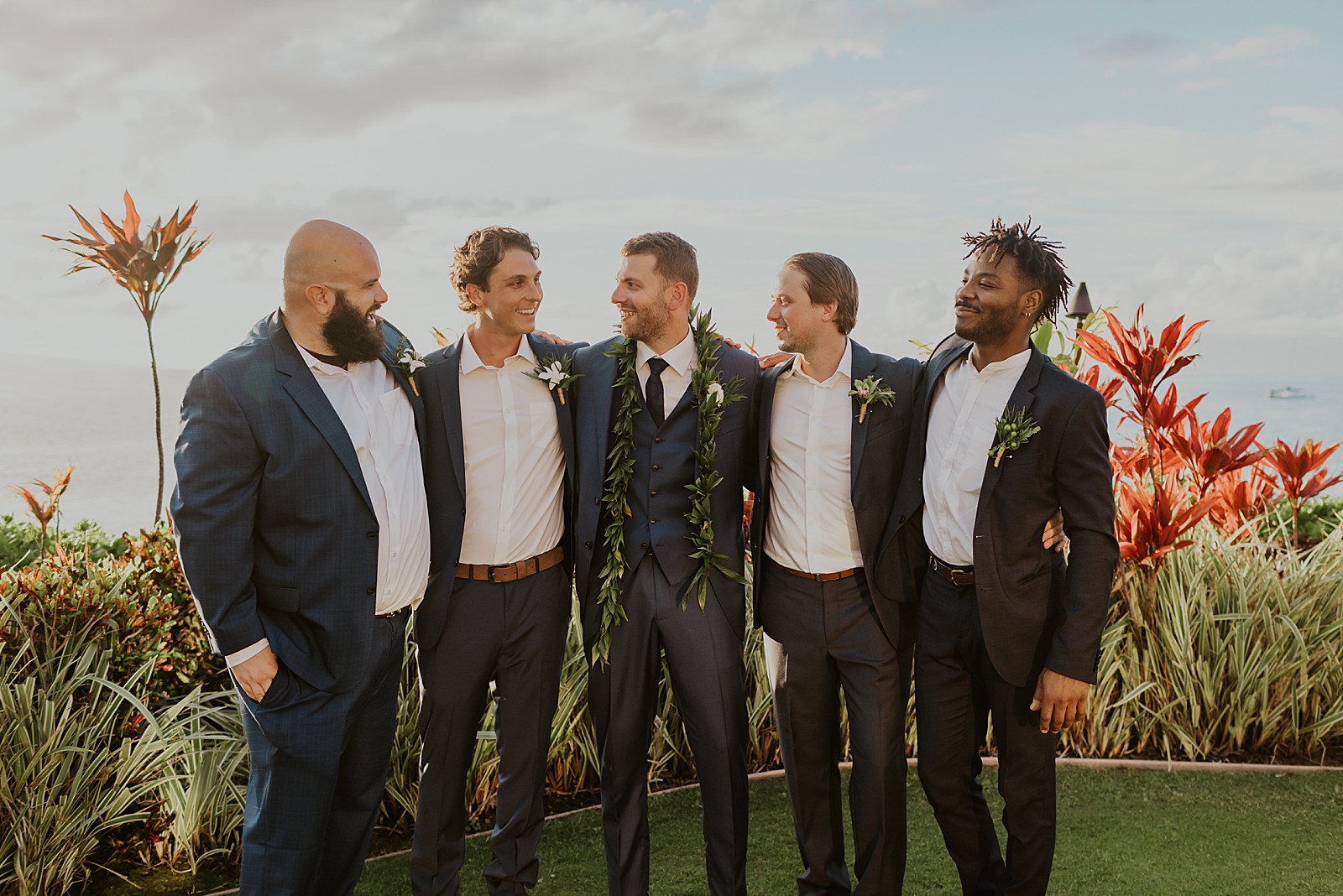 Groom and Groomsmen looking at each other with arms around each other outside