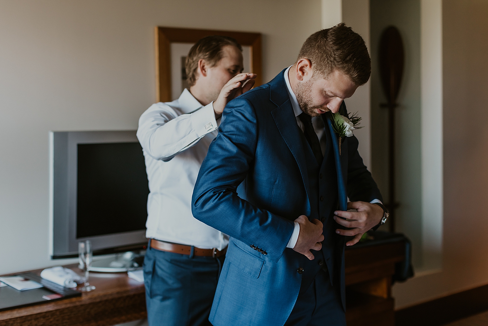 Groom Getting Ready putting on jacket inside