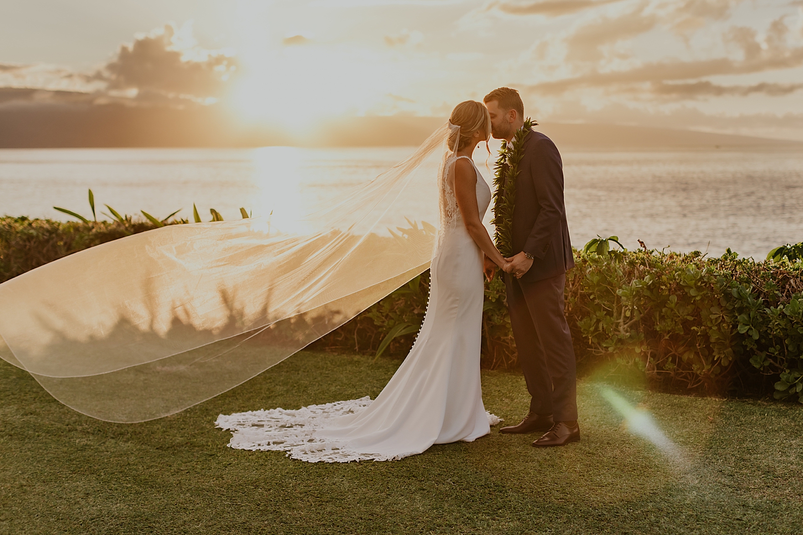 Bride and Groom kissing by the ocean side with veil flowing