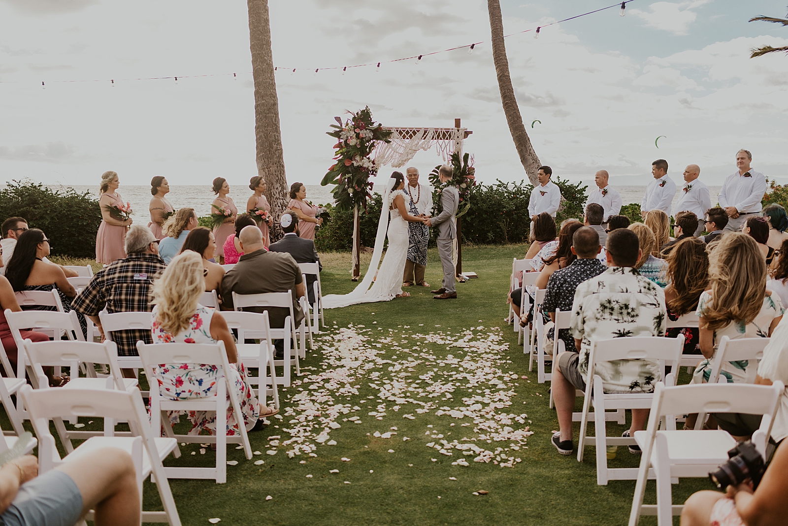 Wide shot of Bride and Groom in front of officiant with wedding party and guests for outdoor Ceremony in front of the ocean
