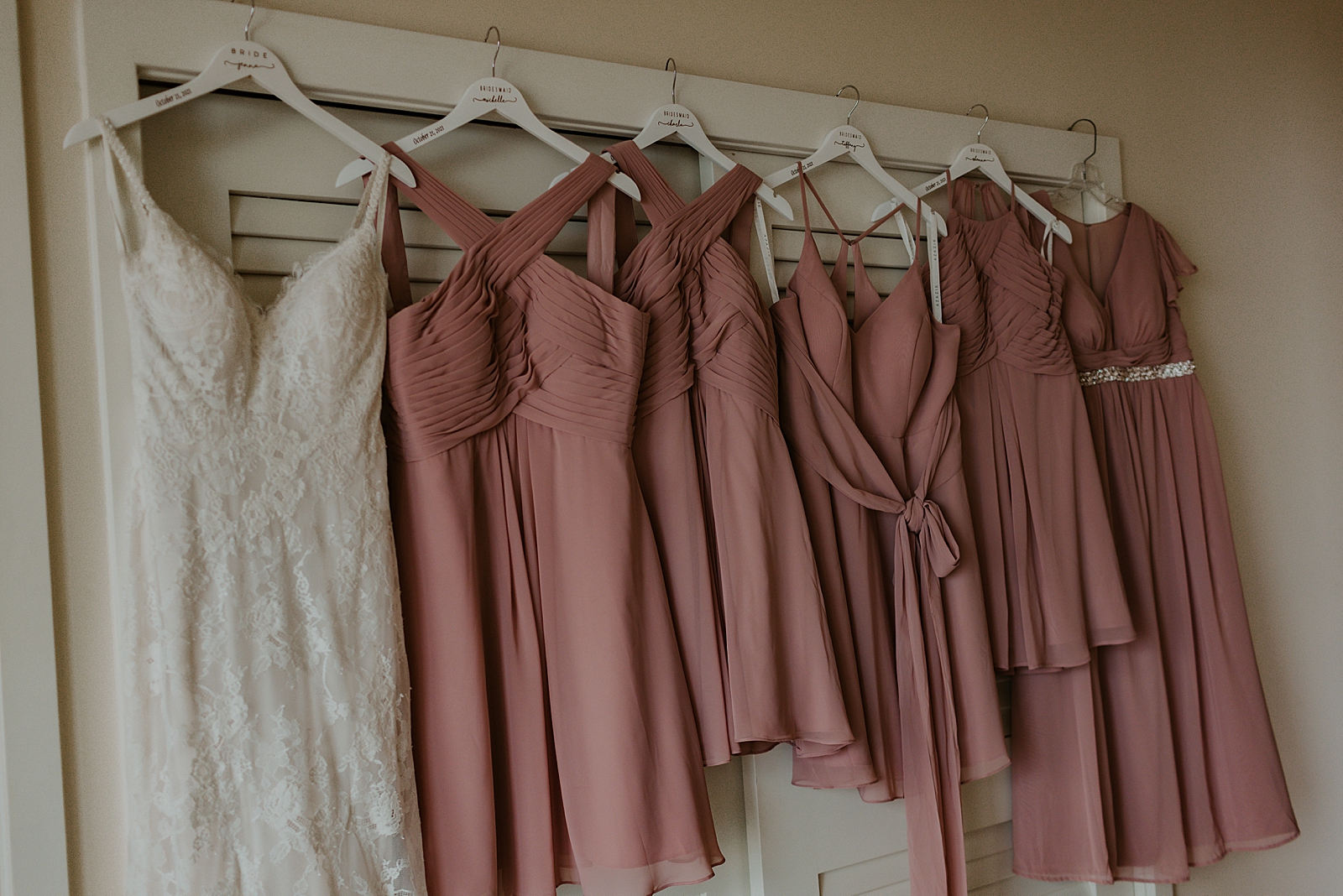 Wedding dress and Bridesmaid dresses hanging together in a row