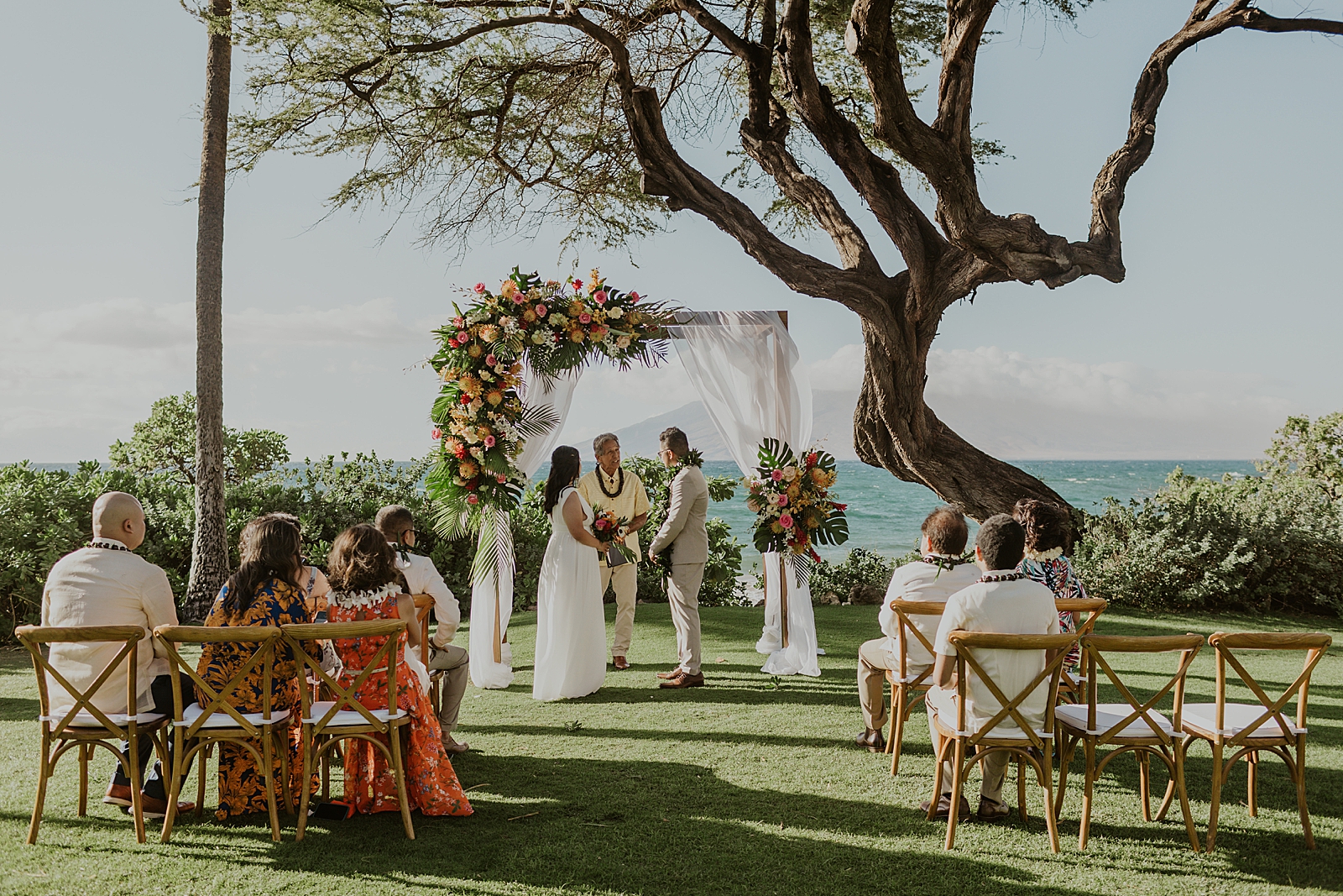 Wide shot of intimate Wedding Ceremony in front of the ocean on grass
