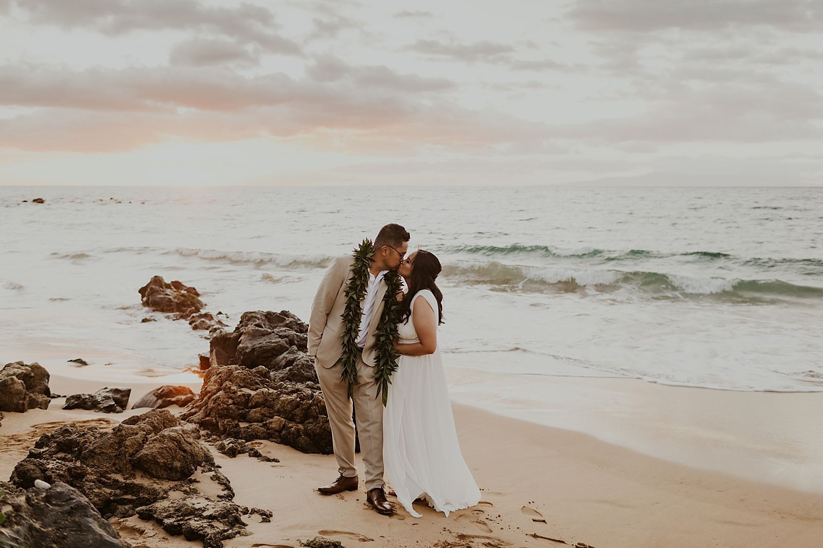 Bride and Groom kissing on the beach as waves come in