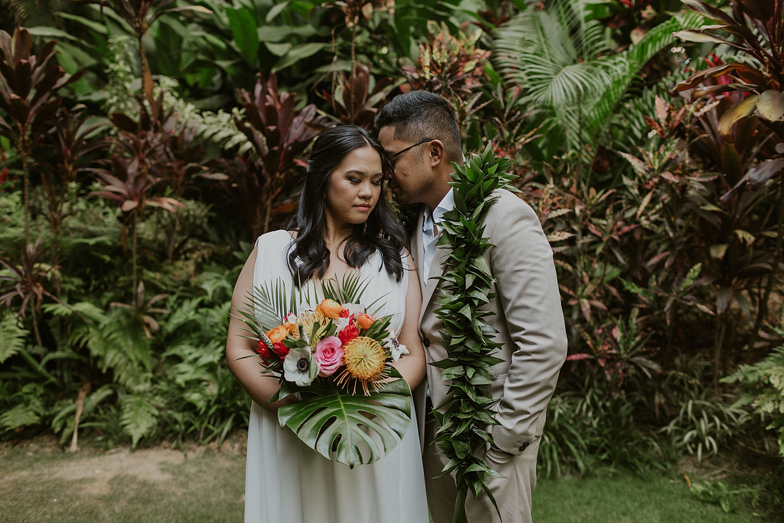 Groom nuzzling Bride with tropical greenery around them