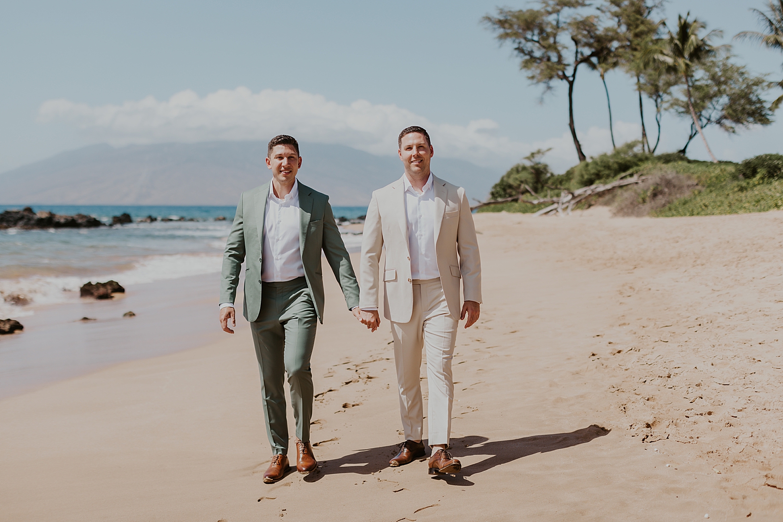 Grooms holding hands and walking on the beach