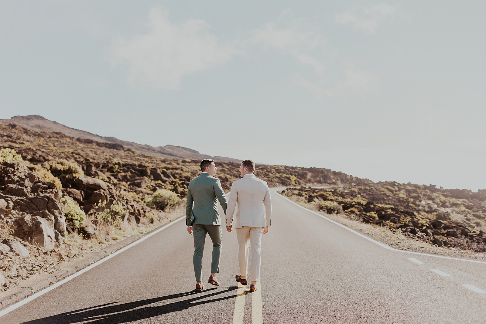 Grooms holding hands and walking on open one way road