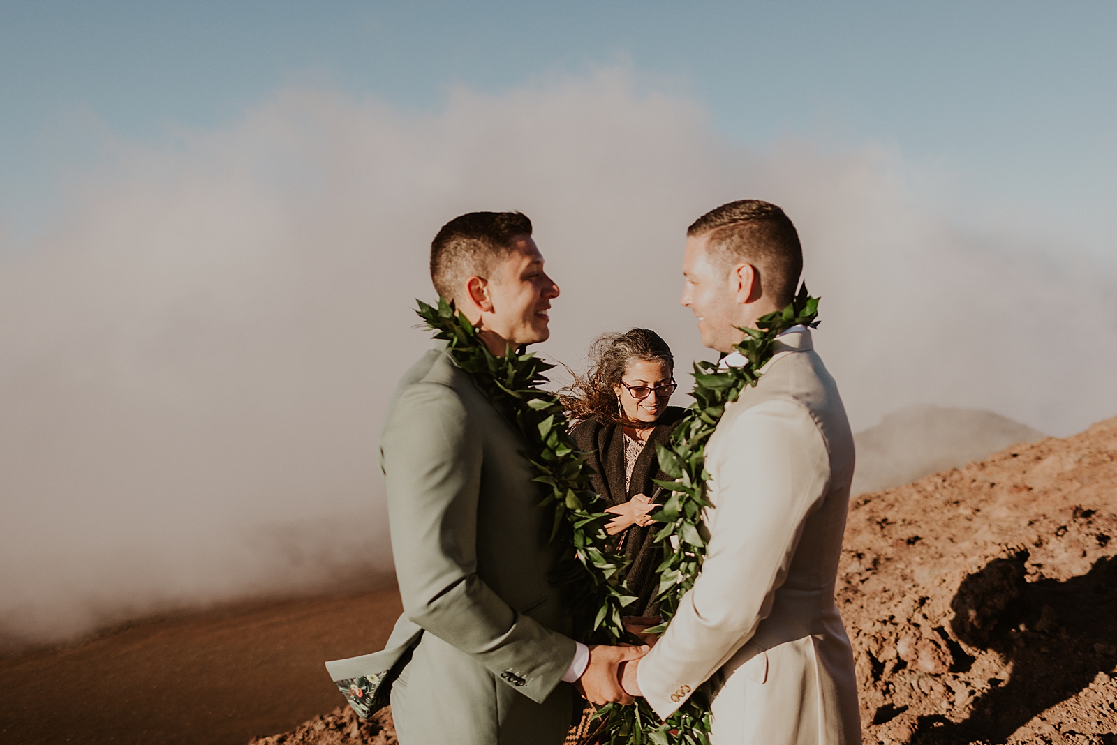 Grooms holding hands and looking at each other listening to the officiant