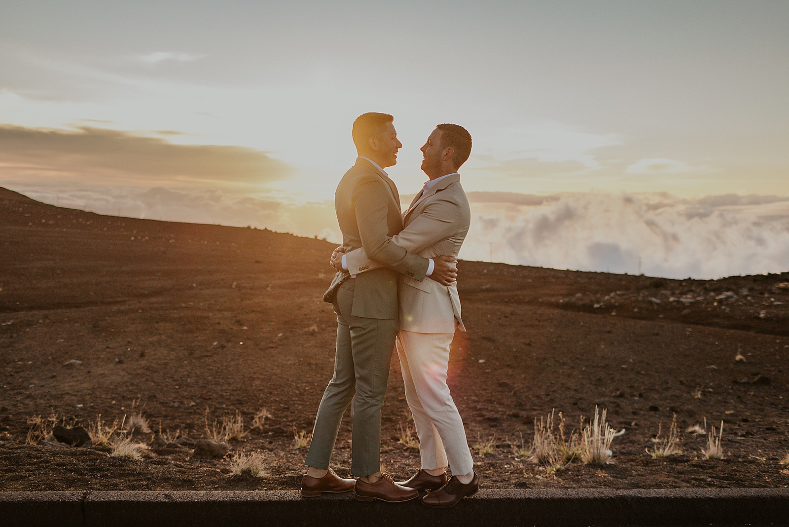 Grooms hugging each other by the side of the road with the sun setting