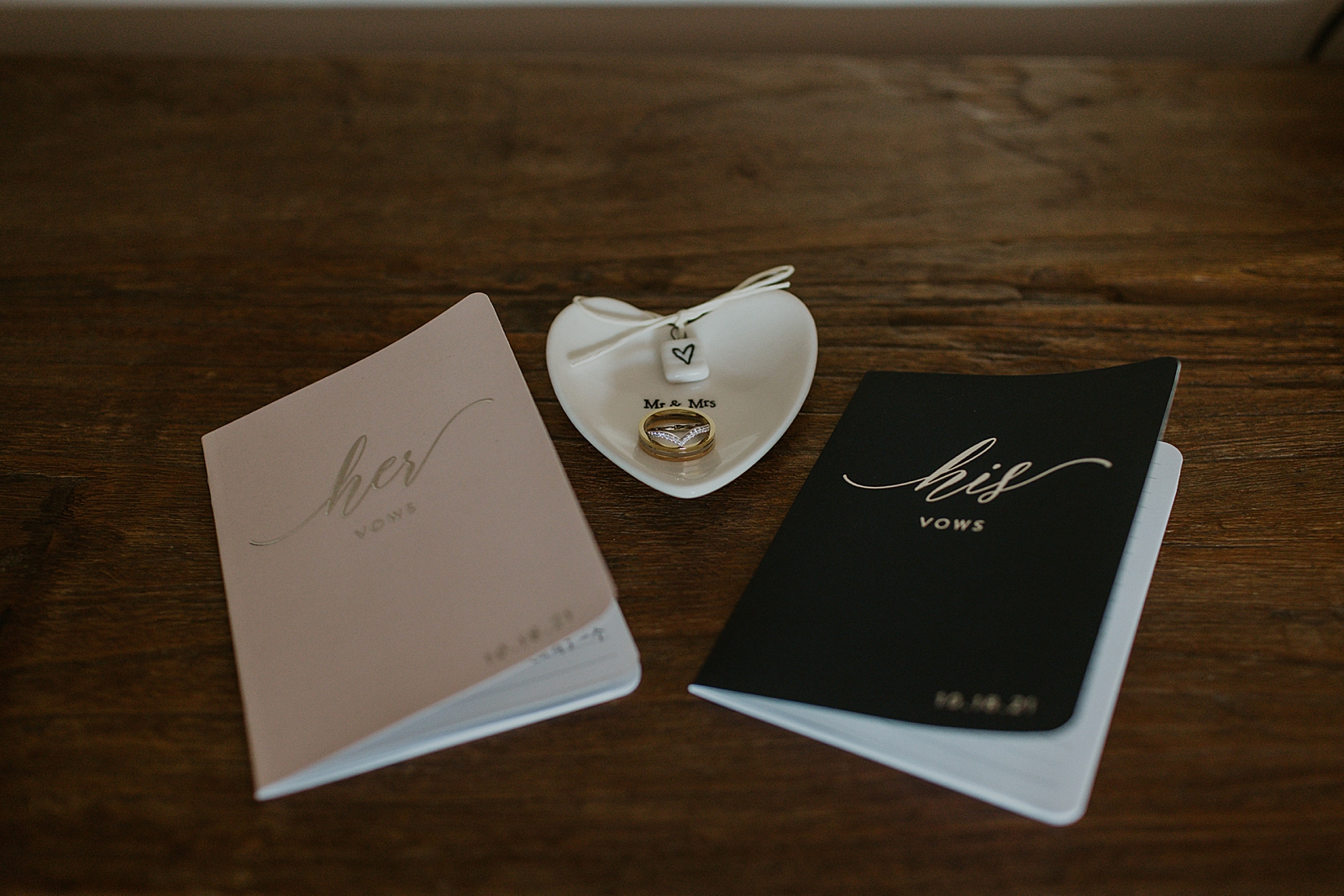Detail shot of his and her vow books with wedding bands
