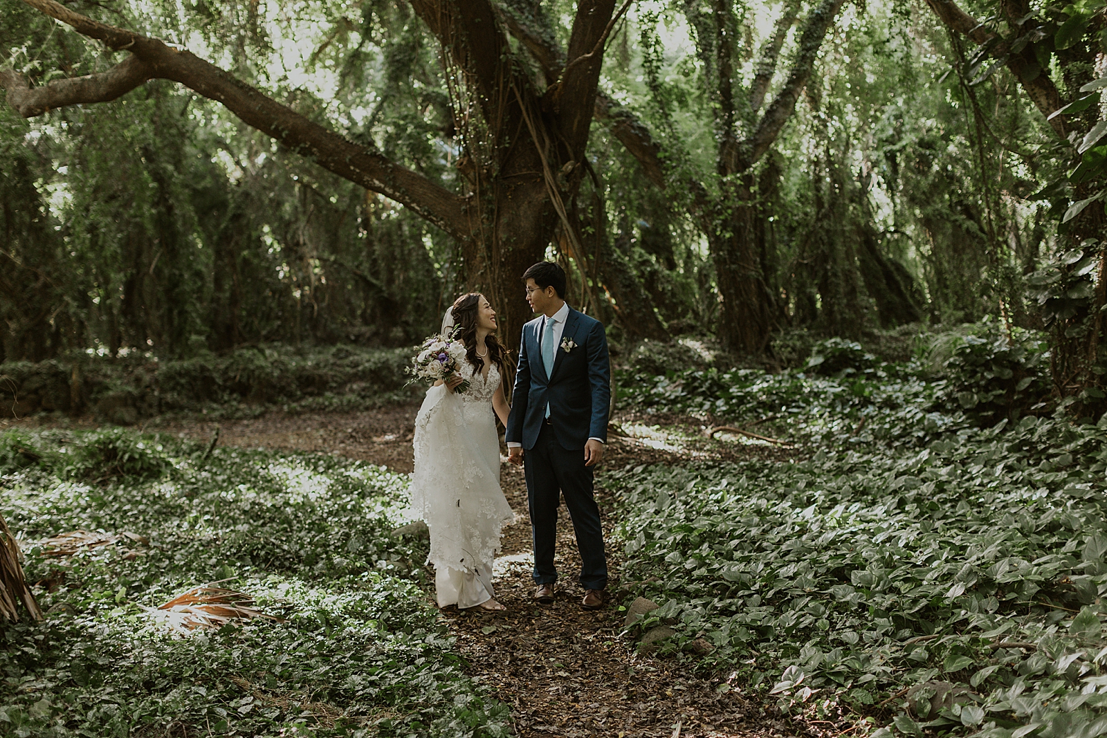 Bride and Groom looking at each other in front of a tree in the forest