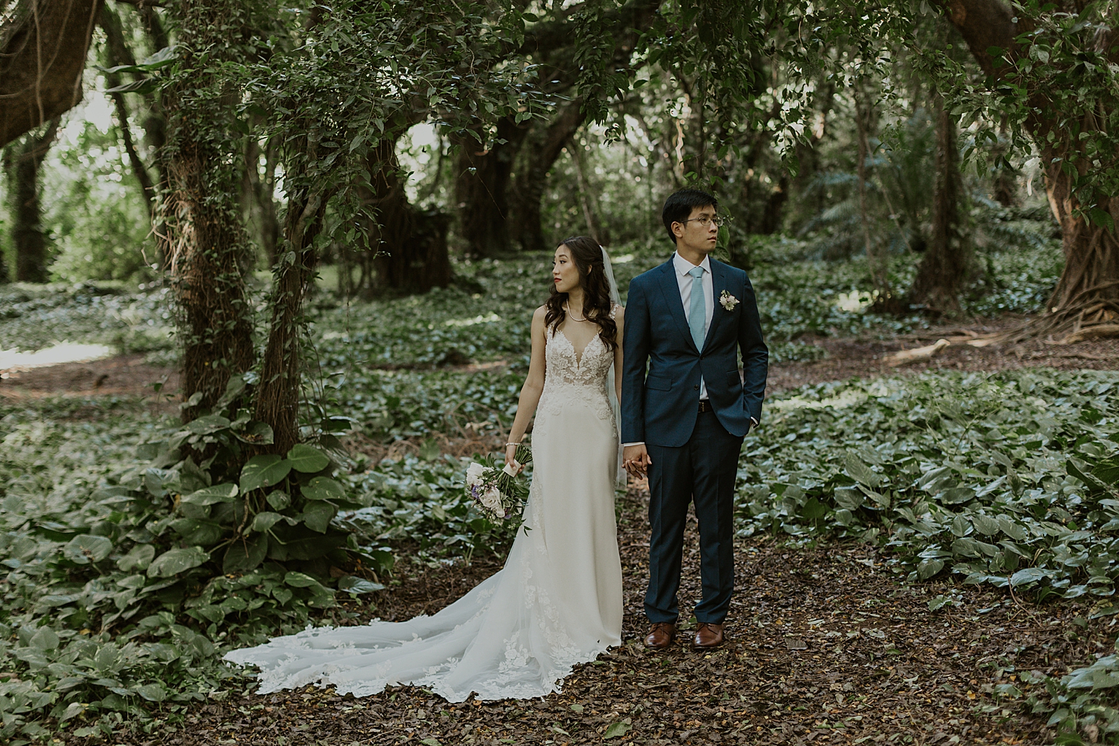 Bride and Groom holding hands and looking the opposite way in the forest