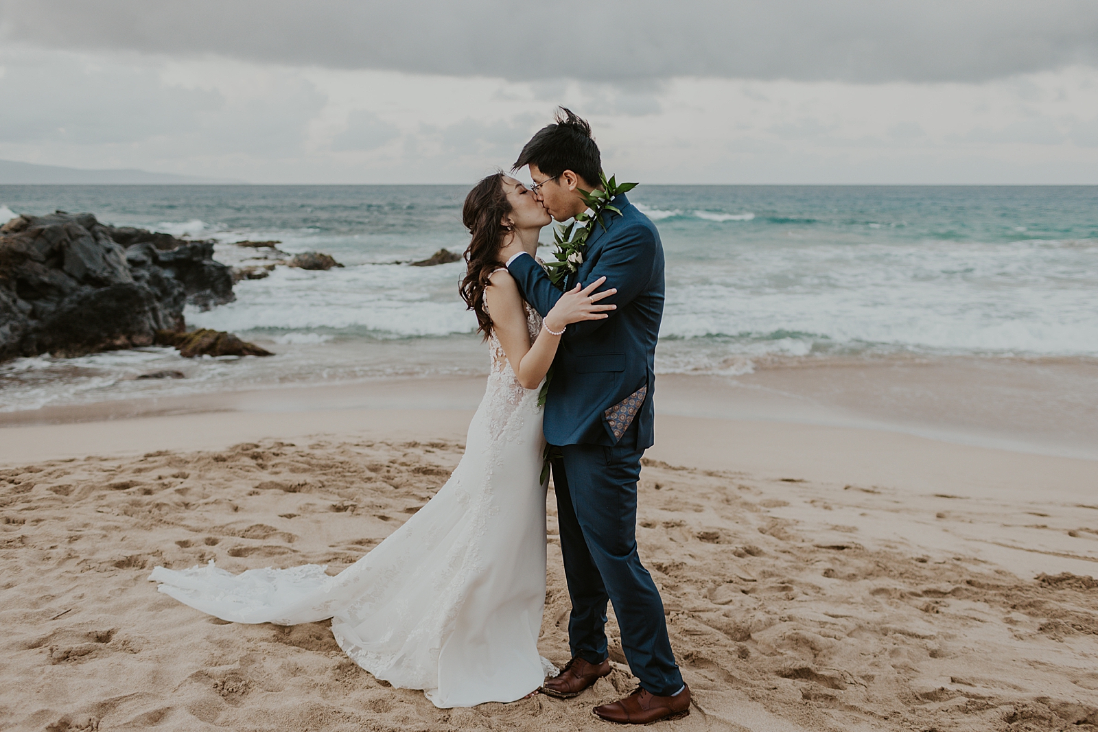 Bride and Groom having a passionate kiss on the beach in front of the water