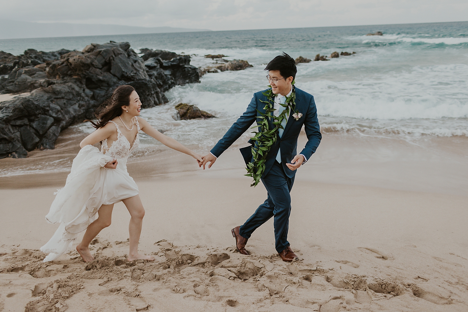 Bride and Groom running on the sand of the beach having fun