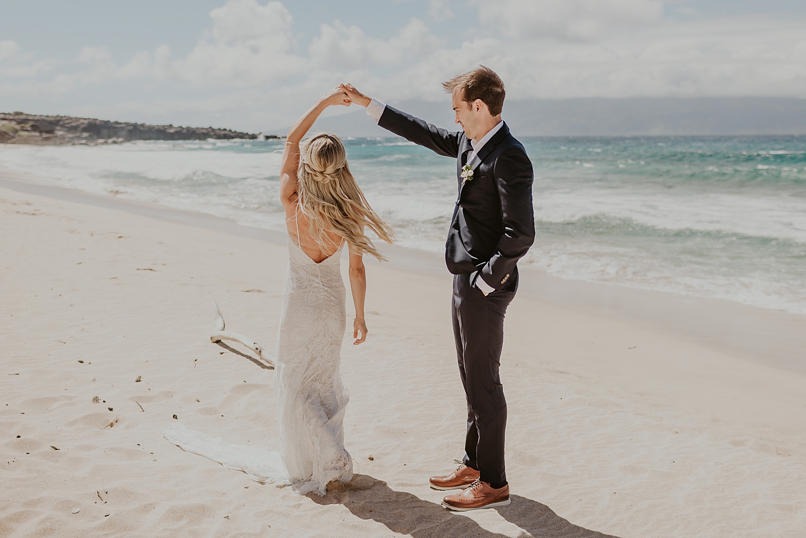 Bride twirling by Groom's hand on the sand of the beach