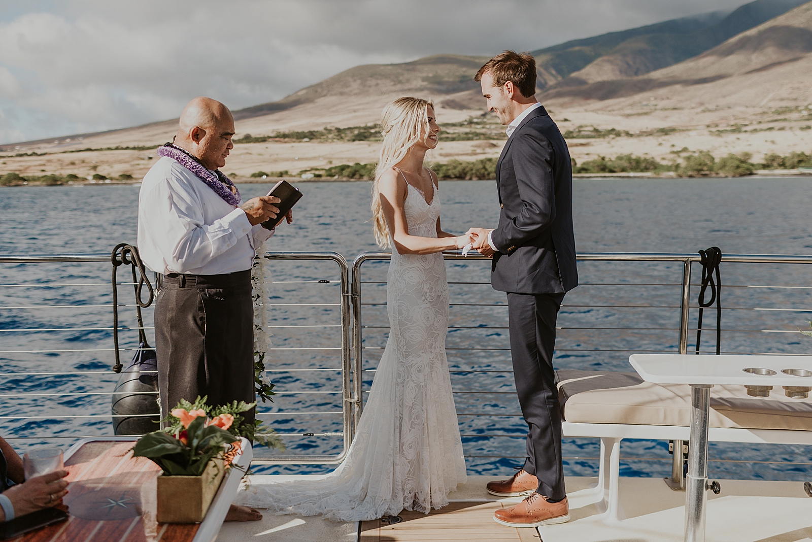 Bride and Groom holding hands and listening to officiant on the boat