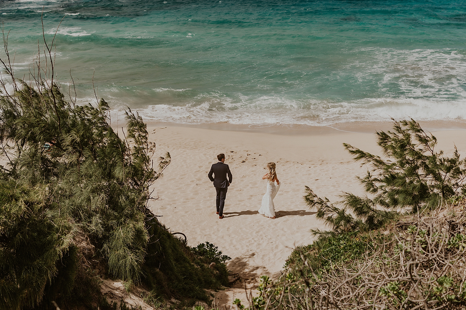 Overhead Shot of Bride and Groom walking on the beach, ocean waves coming in