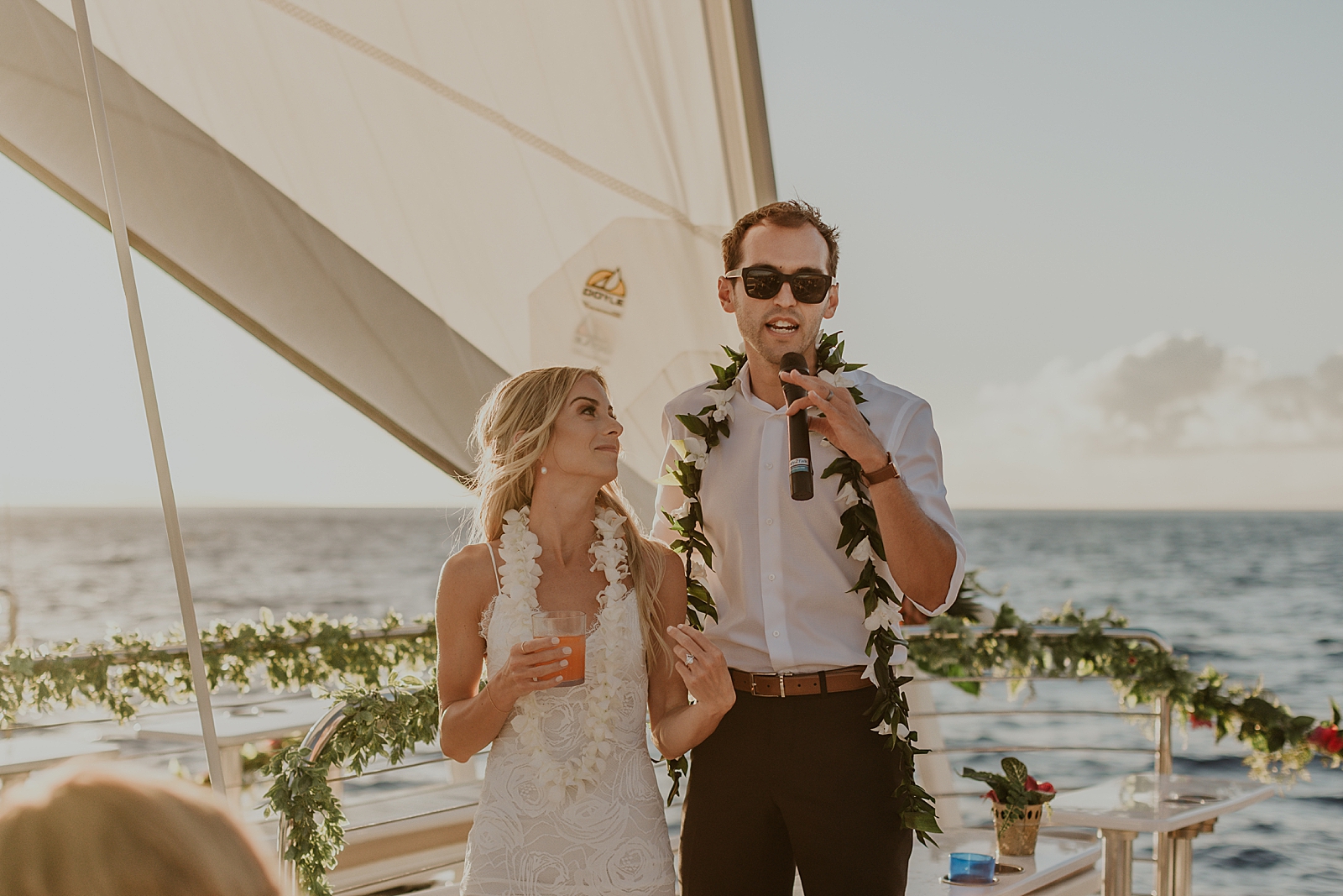 Groom giving speech with Bride next to him with the ocean behind them