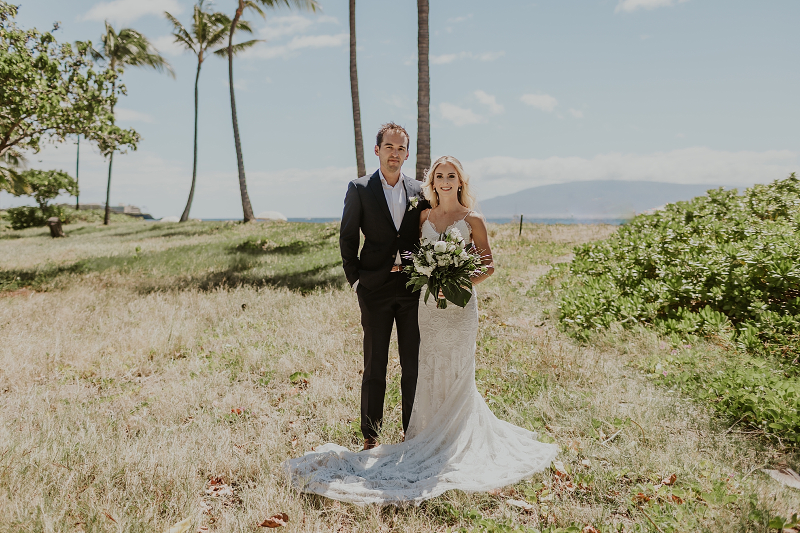 Bride and Groom together on greenery by the beach with tall palm trees